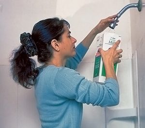 Woman in shower holding milk carton under shower head